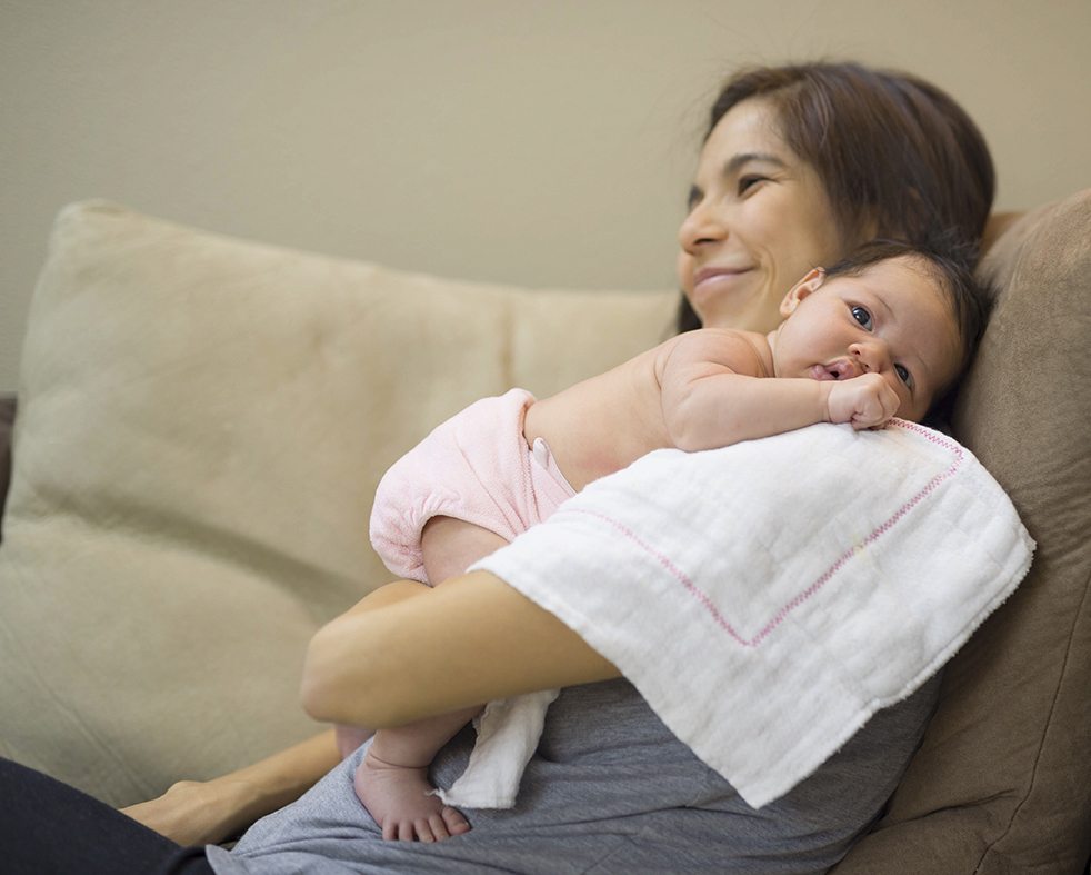mother holding newborn baby on a comfy chair